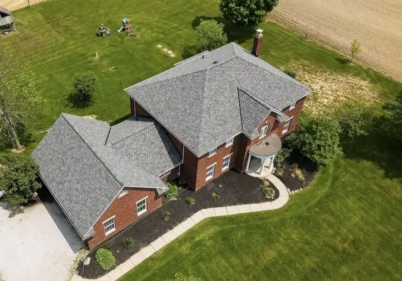 Aerial view of a new gray asphalt shingle roof on a two-story brick home